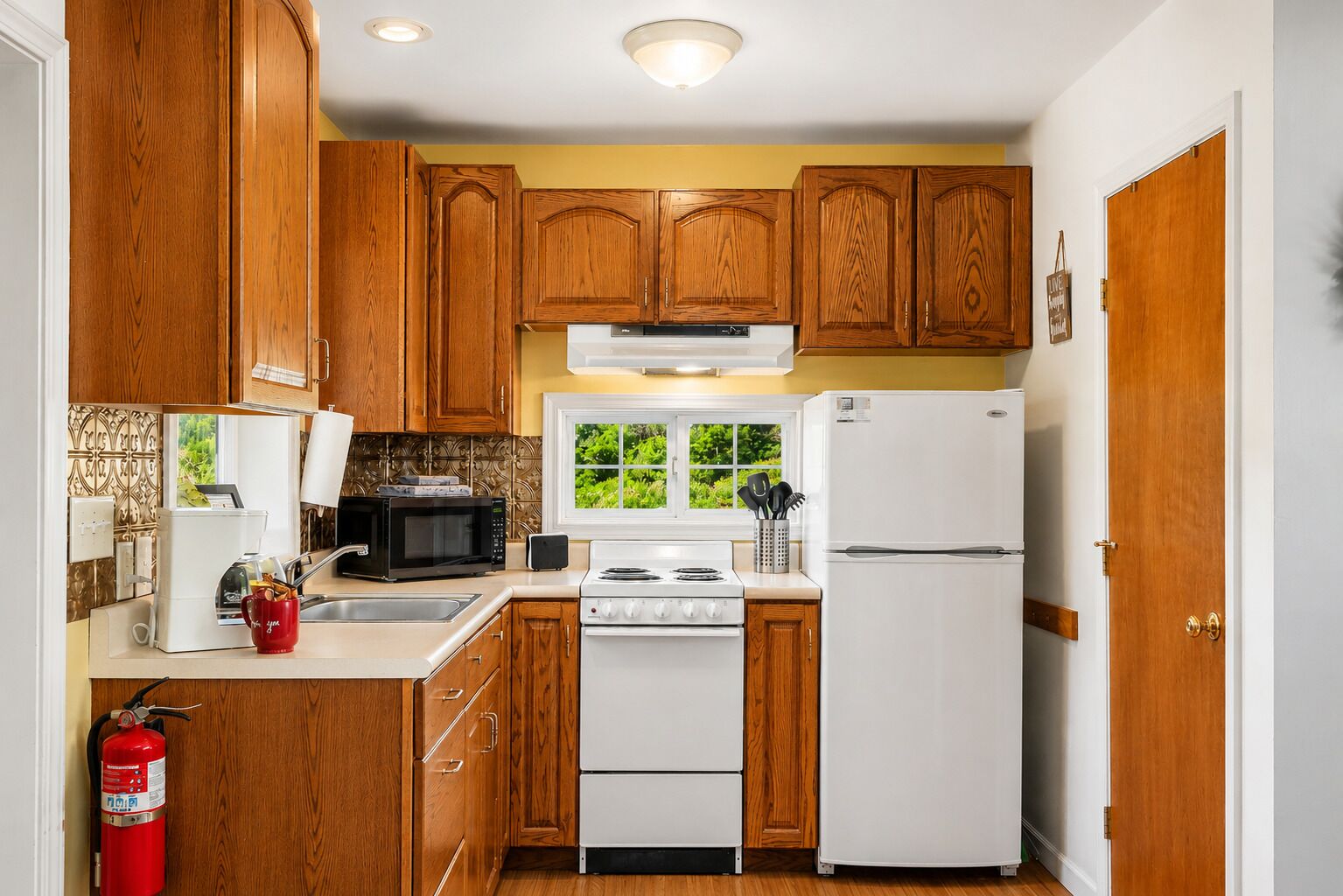 A kitchen with wooden cabinets, a white stove, a microwave, and a refrigerator.