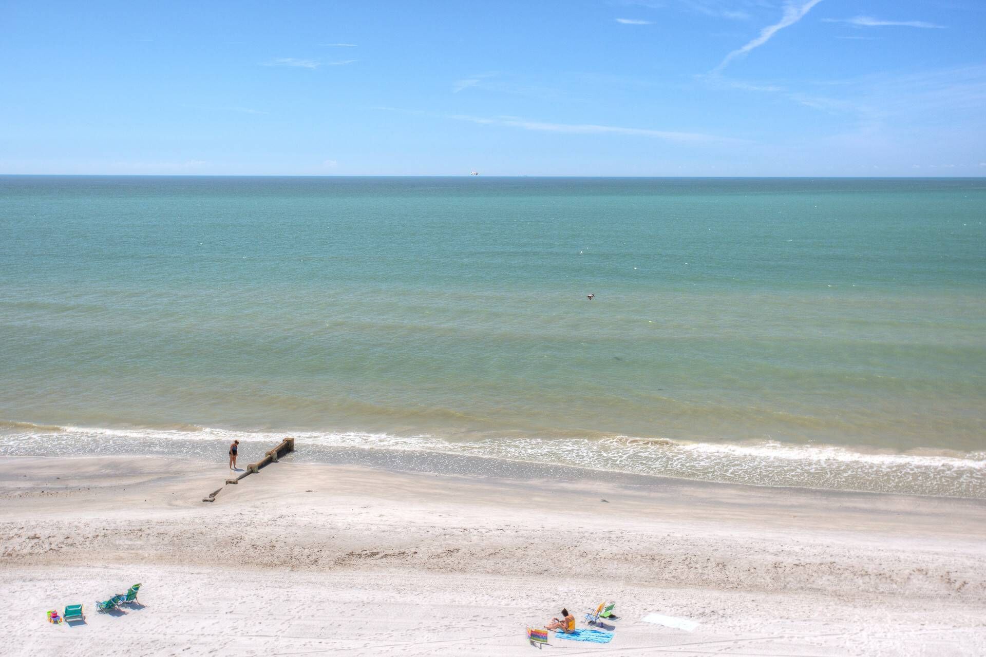 Une plage avec un ciel dégagé, une eau calme et un rivage sablonneux.