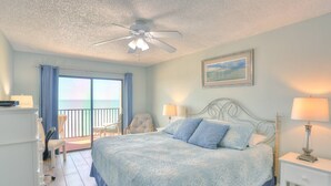 Une chambre à coucher avec un lit, une chaise, un bureau et une vue sur l’océan.