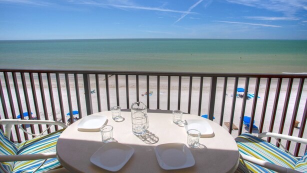 Une table dressée pour deux personnes, avec vue sur la plage et l’océan.