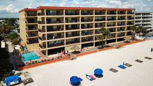 Et hotel med flere etager, altaner, en swimmingpool og et strandareal med liggestole.