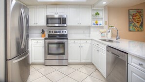 A modern kitchen with white cabinets, stainless steel appliances, and a tiled floor.