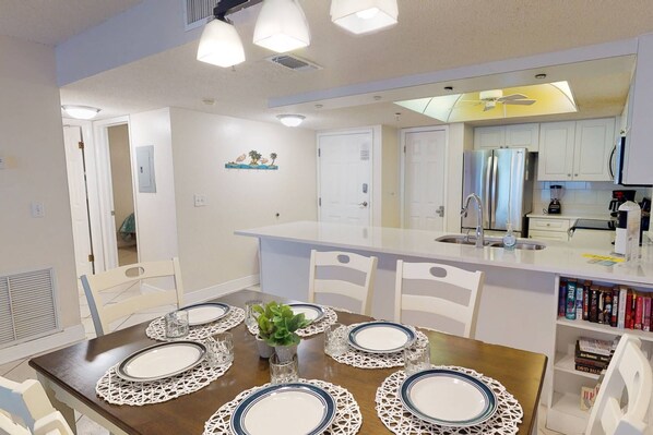 Una cocina moderna con armarios blancos, un refrigerador de acero inoxidable y una isla integrada con pileta.