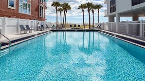 A rectangular swimming pool with clear blue water, surrounded by a white fence, and palm trees in the background. - Incredible Beachfront View Private Balcony! 2 King Bedrooms, Pool & Hot Tub. Quiet and Relaxing Unit (Madeira Beach)