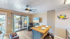 Une cuisine moderne avec un îlot central en bois, un ventilateur de plafond et un téléviseur diffusant une émission intitulée « Island Realty ».