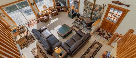 A spacious living room with a large sectional sofa, a fireplace, and a stone wall.
