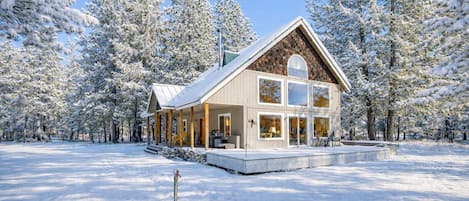 A cabin with a large porch, multiple windows, and a snow-covered landscape.