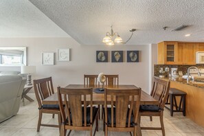 A dining area with a wooden table and chairs, a chandelier, and artwork on the wall.