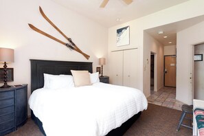 A hotel room with a large bed, two bedside tables, a wardrobe, and a door leading to another room. - Ski in/Ski Out Condo in Main Plaza - Corner Unit - Views of the Slopes (Durango)