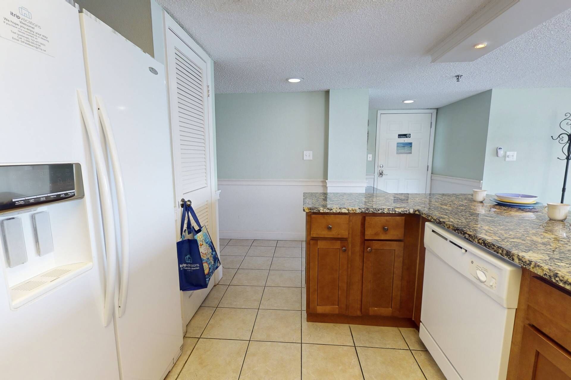 A compact kitchen with white appliances, wooden cabinets, and a granite countertop.