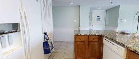 A compact kitchen with white appliances, wooden cabinets, and a granite countertop.