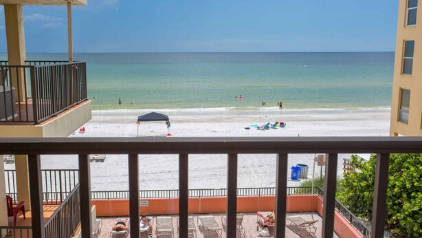 Un balcon avec vue sur la plage, comprenant des chaises longues et un espace piscine.