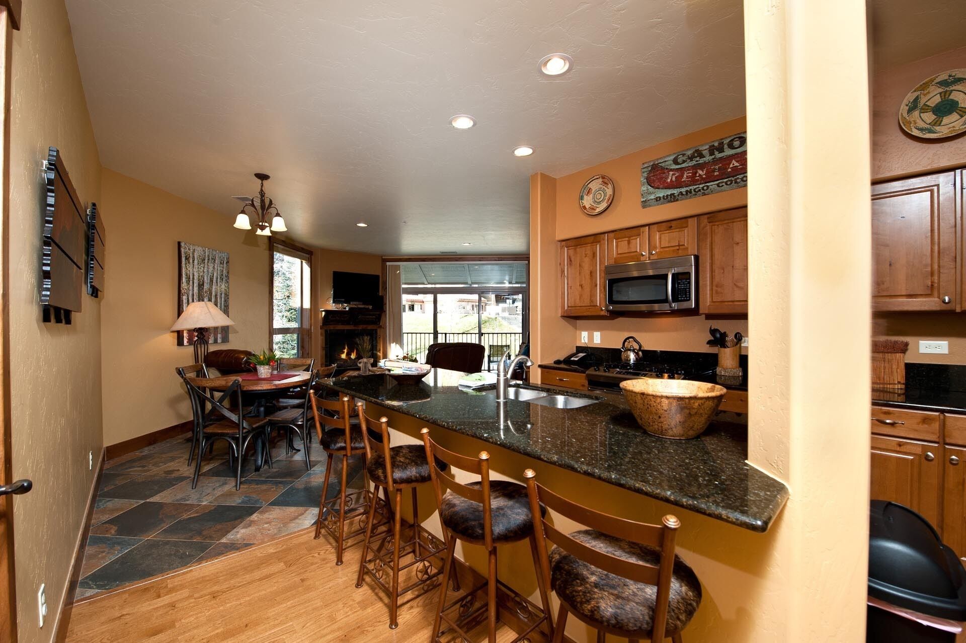 A kitchen with a large island, wooden bar stools, a microwave, and a coffee maker.