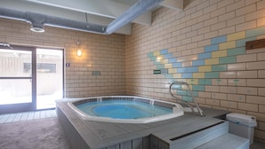 Un espace détente avec un jacuzzi, des marches en bois et un mur carrelé sur lequel est affiché un panneau indiquant «Interdiction deverre».