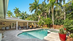 A backyard with a swimming pool, patio furniture, and a covered seating area. - 5/3 Estate-Heated Pool-Hot tub-Beach-for 12 Guests (Hollywood)