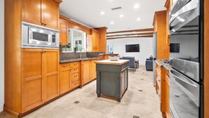 A modern kitchen with wooden cabinets, stainless steel appliances, and a central island. - 5/3 Estate-Heated Pool-Hot tub-Beach-for 12 Guests (Hollywood)