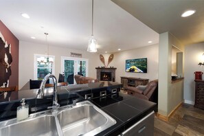A modern kitchen with a large island, stainless steel appliances, and a fireplace.