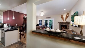Une cuisine moderne dotée d’un îlot central, d’un coin repas avec un canapé en cuir marron et d’une cheminée agrémentée d’objets décoratifs.