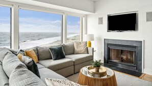 A modern living room with a large sofa, a fireplace, and a television. - Outstanding condo in Wild Dunes with two oceanfront decks and pool access (Isle of Palms)
