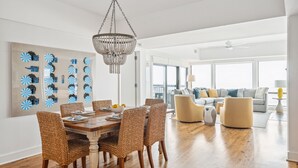 A spacious living room with a wooden floor, a large chandelier, and a modern sofa set. - Outstanding condo in Wild Dunes with two oceanfront decks and pool access (Isle of Palms)
