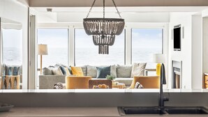A modern kitchen with a large window overlooking the sea, a chandelier, and a sofa with cushions. - Outstanding condo in Wild Dunes with two oceanfront decks and pool access (Isle of Palms)