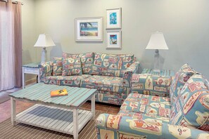 Uma sala de estar aconchegante com um sofá estampado, uma mesinha de centro de madeira e duas luminárias fixadas na parede.