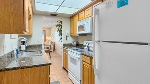 A kitchen with wooden cabinets, a microwave, a stove, and a refrigerator.
