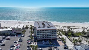 A beachfront hotel with multiple floors, a parking lot, and a beach in the background.