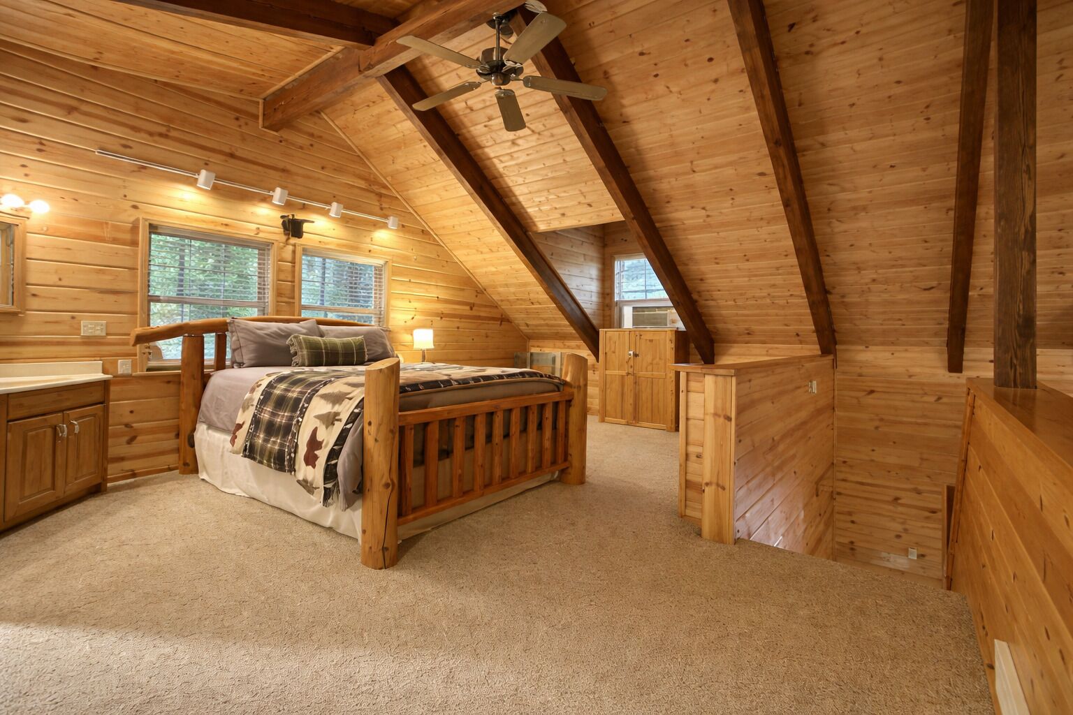 Une chambre mansardée chaleureuse, avec un lit en bois, un bureau et une armoire.