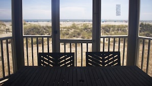 A beach view from a wooden deck with a table and chairs, overlooking the beach and dunes. - Oceanfront 1st floor condo with direct beach access from private porch (Isle of Palms)