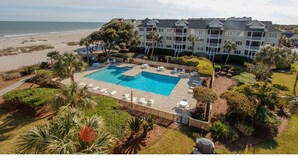 A hotel with a large pool, beach view, and multiple balconies. - Oceanfront 1st floor condo with direct beach access from private porch (Isle of Palms)