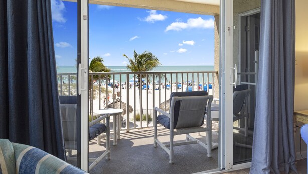 Een balkon met uitzicht op het strand, een tafel en twee stoelen.