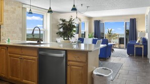 Een ruime woonkamer met keuken, eethoek en uitzicht op de oceaan.
