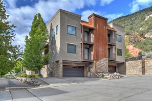 A modern multi-story building with a stone facade, large windows, and a garage.