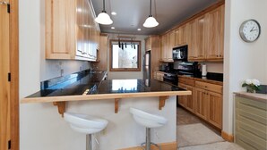 Une cuisine avec des meubles en bois, un plan de travail noir et un évier à deux bacs.
