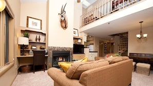 A spacious living room with a fireplace, a sofa set, a dining area, and a staircase leading to an upper level. - Affordable Animas River Valley Townhome - A/C (Durango)