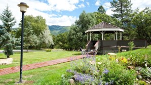 A gazebo with a wooden deck, surrounded by a well-maintained garden with various plants and flowers. - Affordable Animas River Valley Townhome - A/C (Durango)