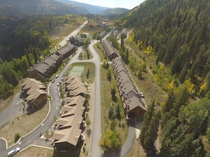 A residential area with multiple houses, a tennis court, and a road.