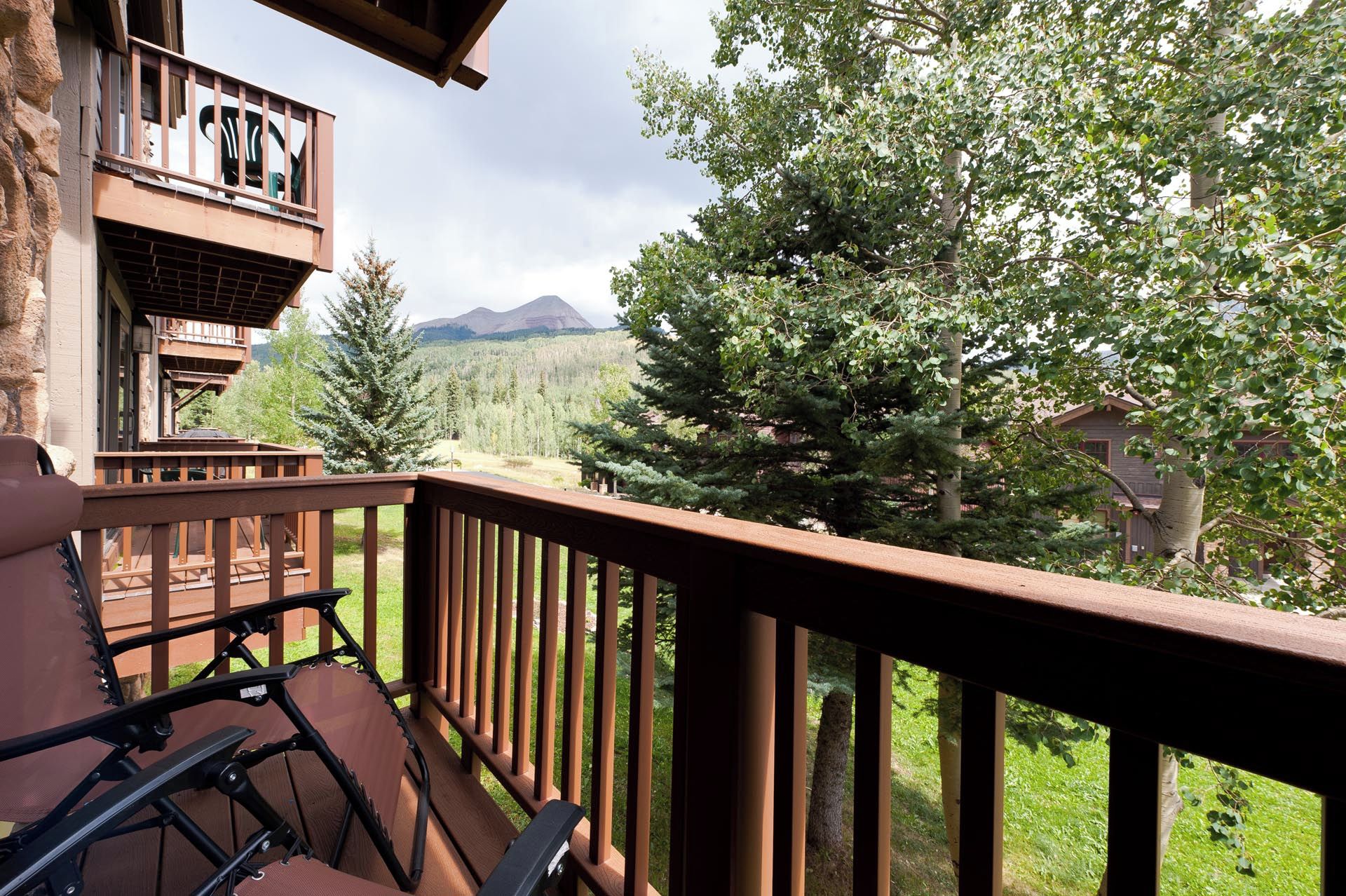 Un balcon avec vue sur une forêt et des montagnes.