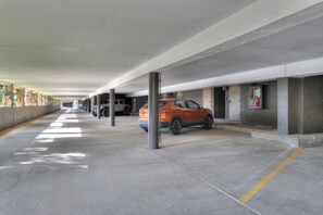 A covered parking garage with concrete pillars, a fire extinguisher mounted on the wall, and a row of parked vehicles including a Jeep and a red SUV. - Cascade Village Condo - Views/Heated Pool/Two Decks (Durango)