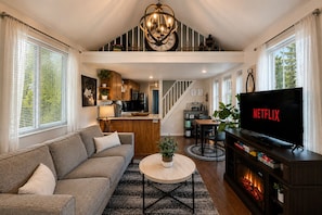A modern living room with a sofa, coffee table, TV, and fireplace.