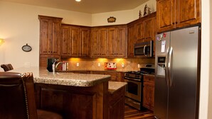 A kitchen with wooden cabinets, a stainless steel refrigerator, a microwave, and a stove.