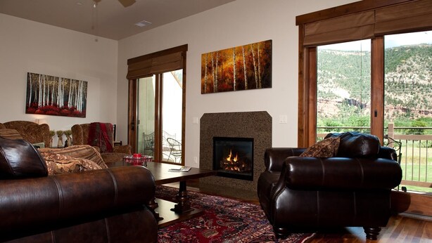 A living room with a fireplace, leather sofas, a patterned rug, and artwork on the walls.
