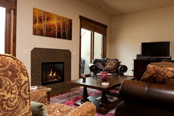 A living room with a fireplace, leather sofas, a coffee table, and a television.