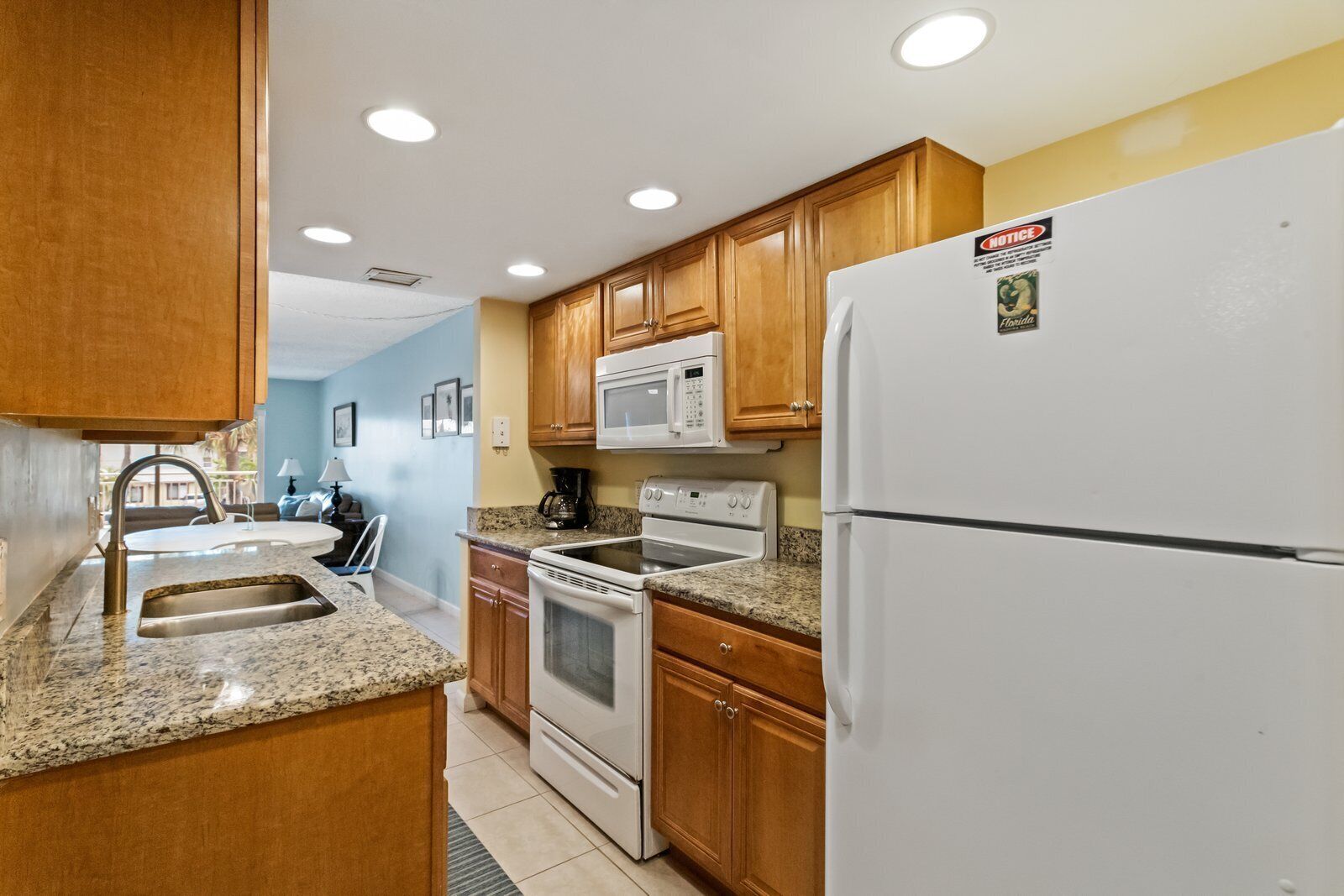 A kitchen with wooden cabinets, a white refrigerator, a microwave, an oven, and a sink.