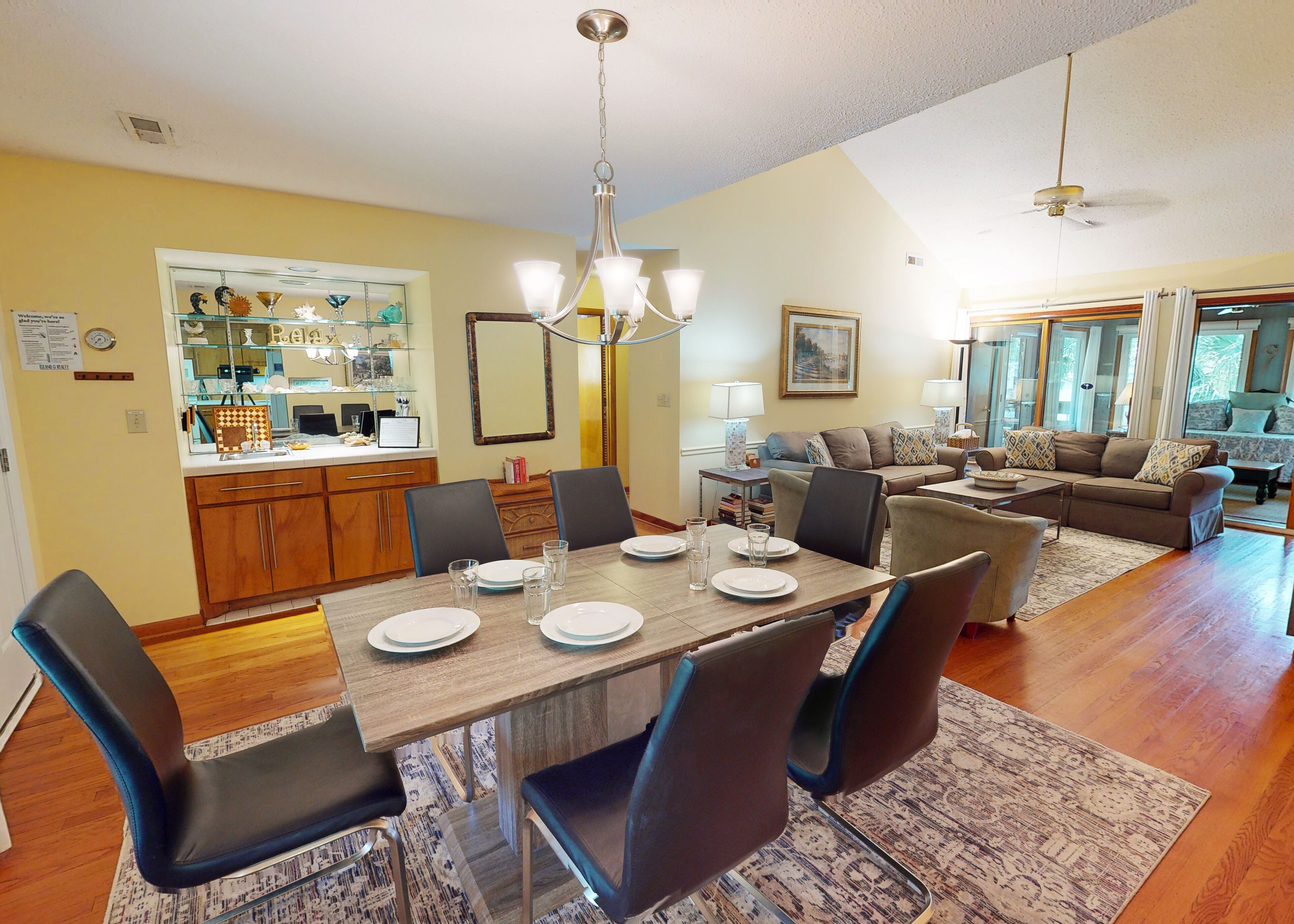 A dining area with a wooden table set for four, surrounded by chairs.