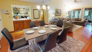 A dining area with a wooden table set for four, surrounded by chairs.