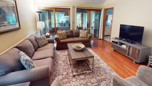 A spacious living room with a large sofa set, a coffee table, and a television on a stand.