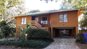 A two-story wooden house with a covered porch, a visible number '910', and a gravel driveway.