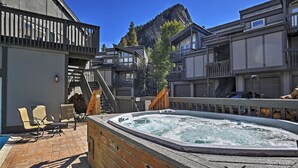 Un área de hidromasaje con terraza de madera, asientos exteriores y montañas al fondo.